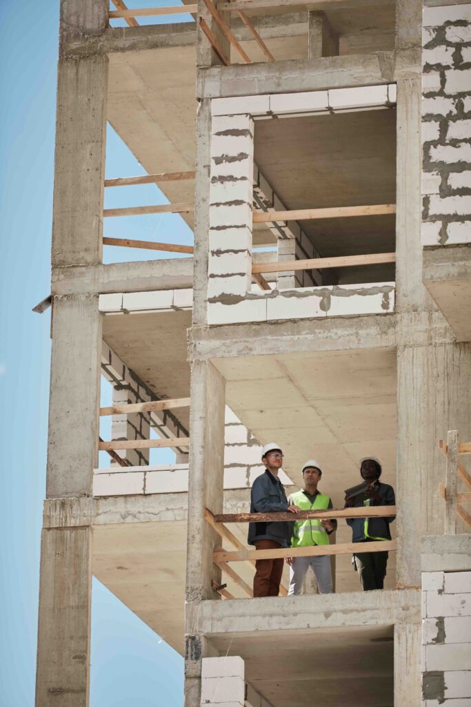 Vertical background image of high rise construction site with group of workers, copy space