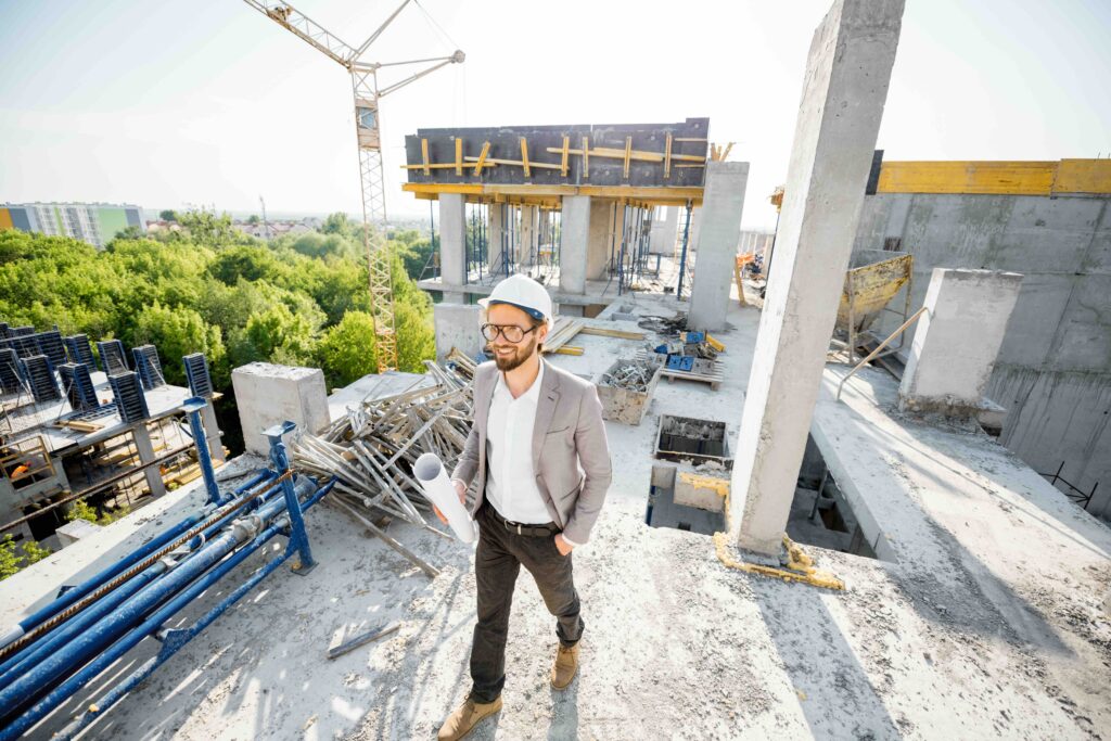 Man supervising the process of house construction walking with drawings on the structure outdoors