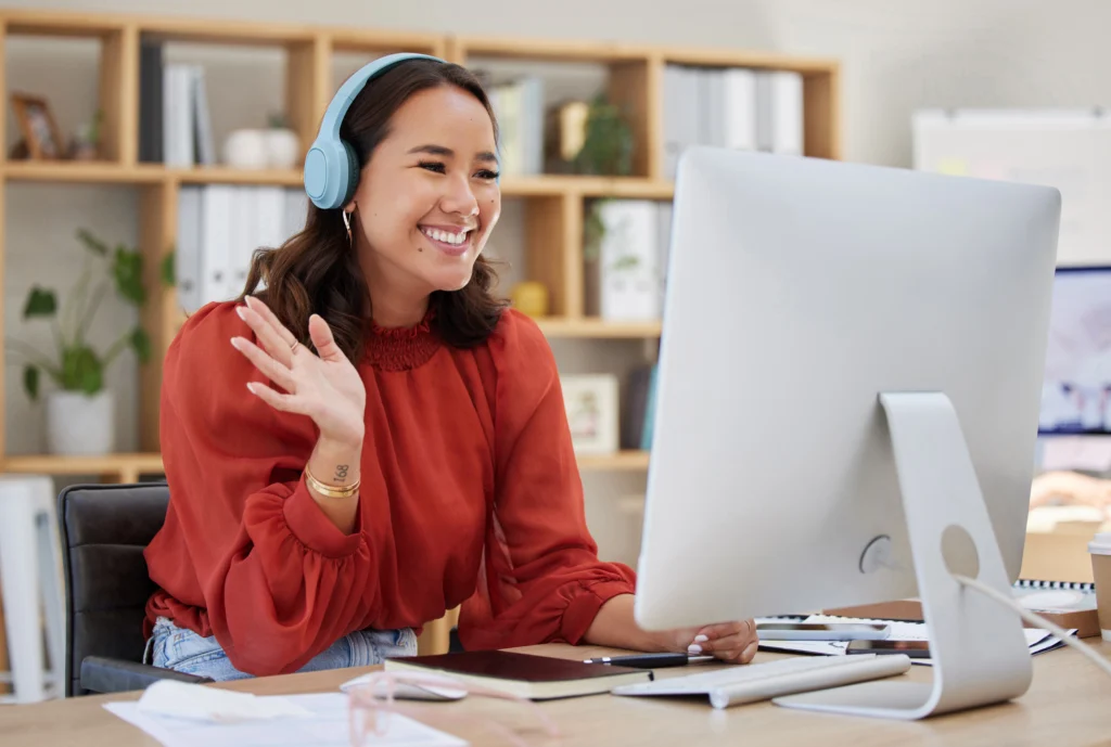 Asian businesswoman waving at webcam wearing wire