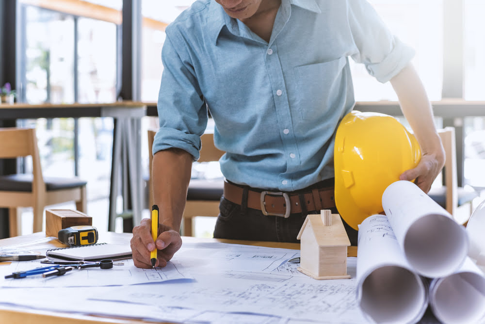a construction manager looking over the plans for a project after writing a successful construction contract