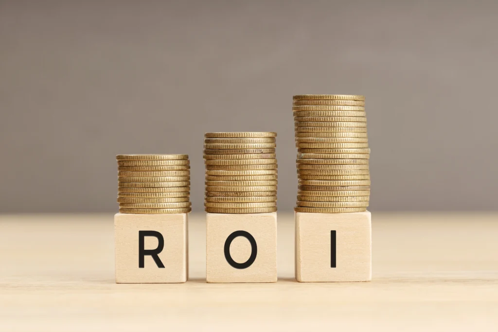 Stacks of coins on wooden blocks spelling ROI to show financial growth
