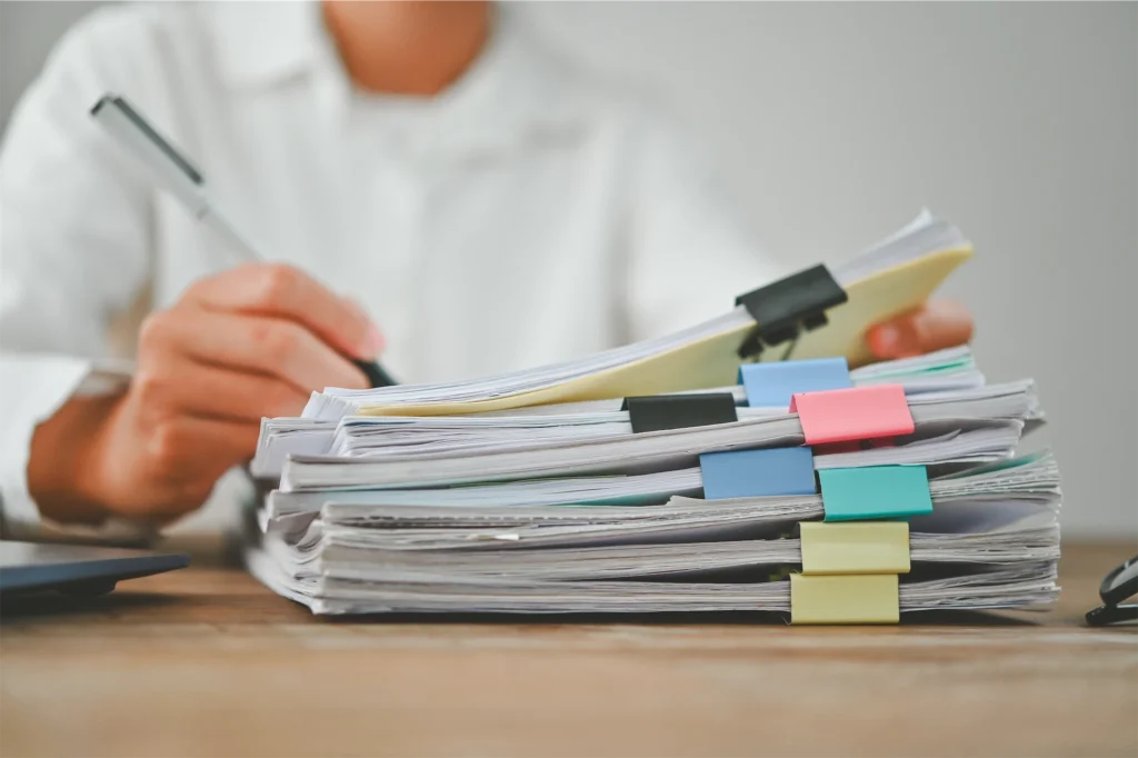 Administrative worker writing notes on organized stack of documents
