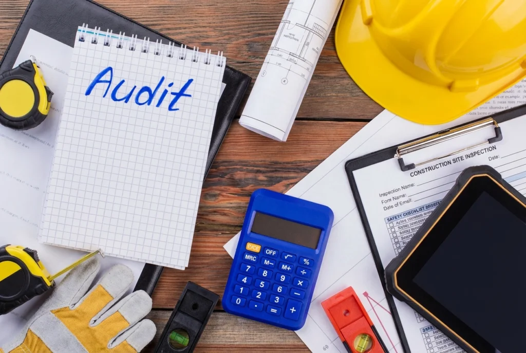 Desk with calculator, hard hat, and construction audit forms