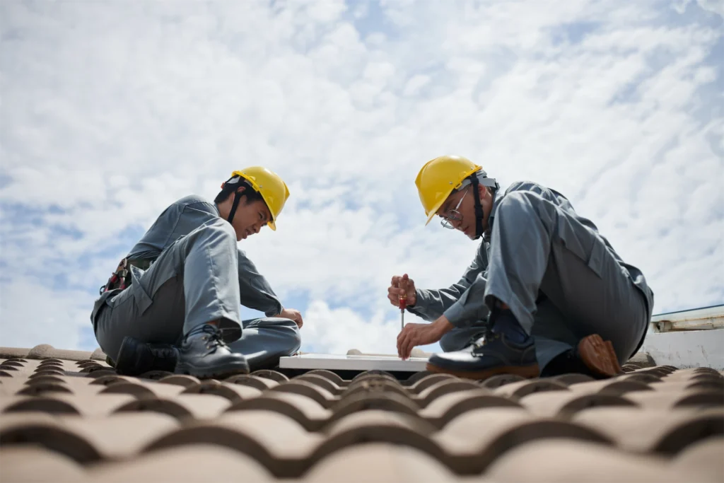 Roofing contractors repairing tile roof with safety gear