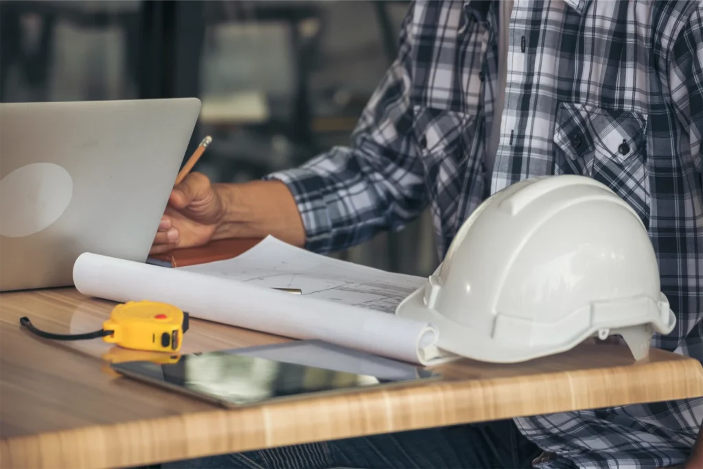 MEP drafting virtual assistant working at desk with laptop and white hard hat