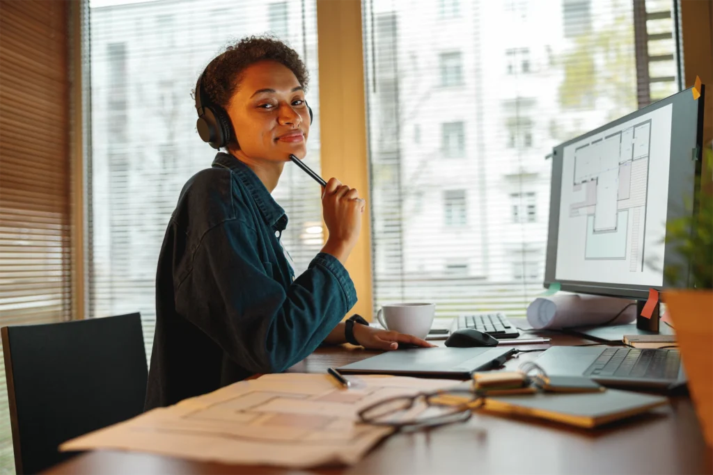 HVAC virtual assistant with headset reviewing plans at desk